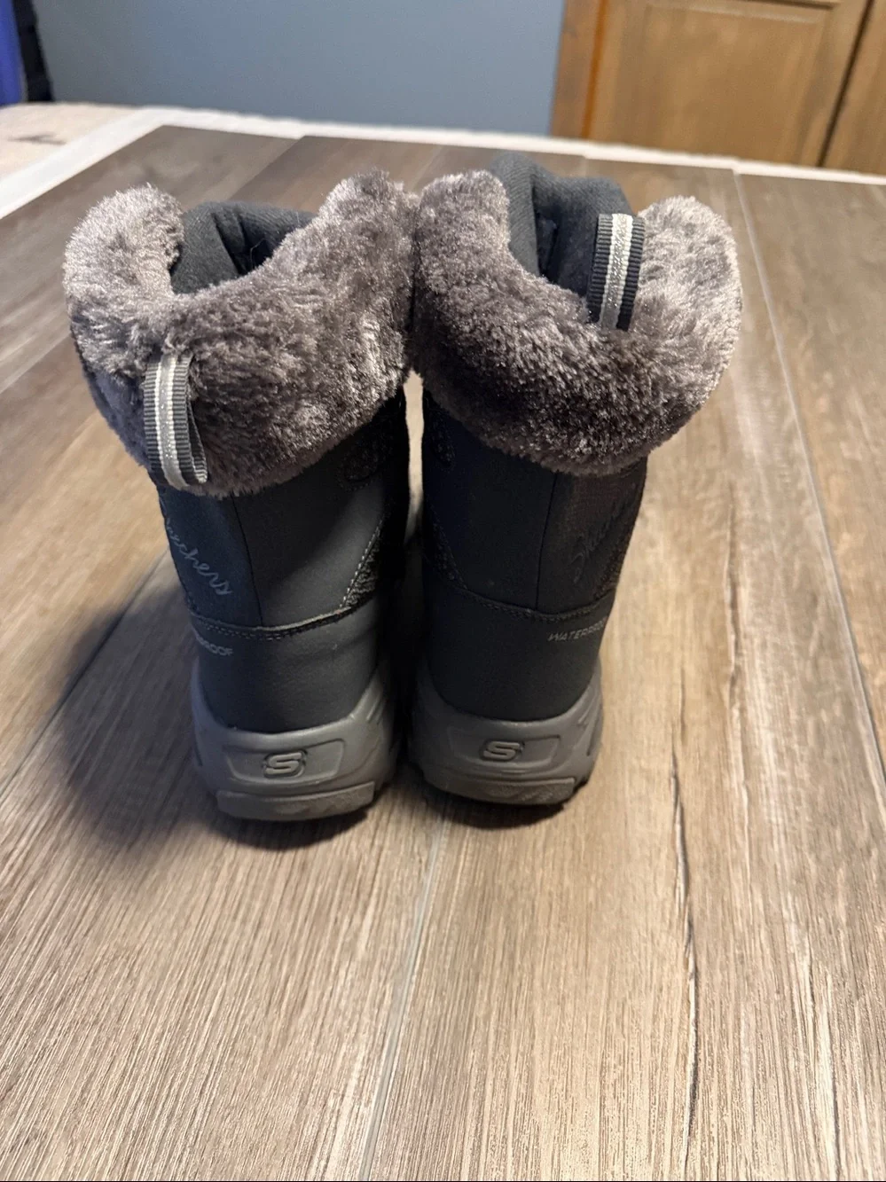 Skechers D'Lites Bomb Cyclone winter boots in a charcoal color, featuring a faux